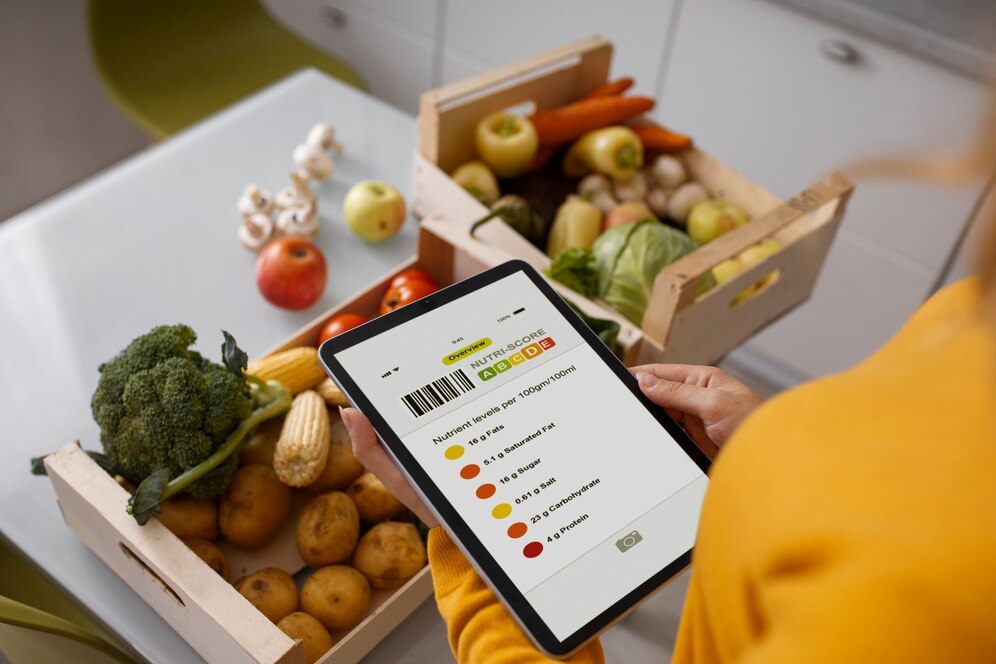A person in a yellow sweater interacts with a tablet displaying nutrient scores, surrounded by fresh fruits and vegetables.