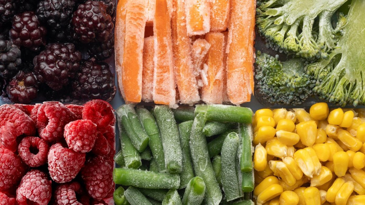A colorful assortment of frozen fruits and vegetables: blackberries, raspberries, carrot sticks, green beans, corn, and broccoli.